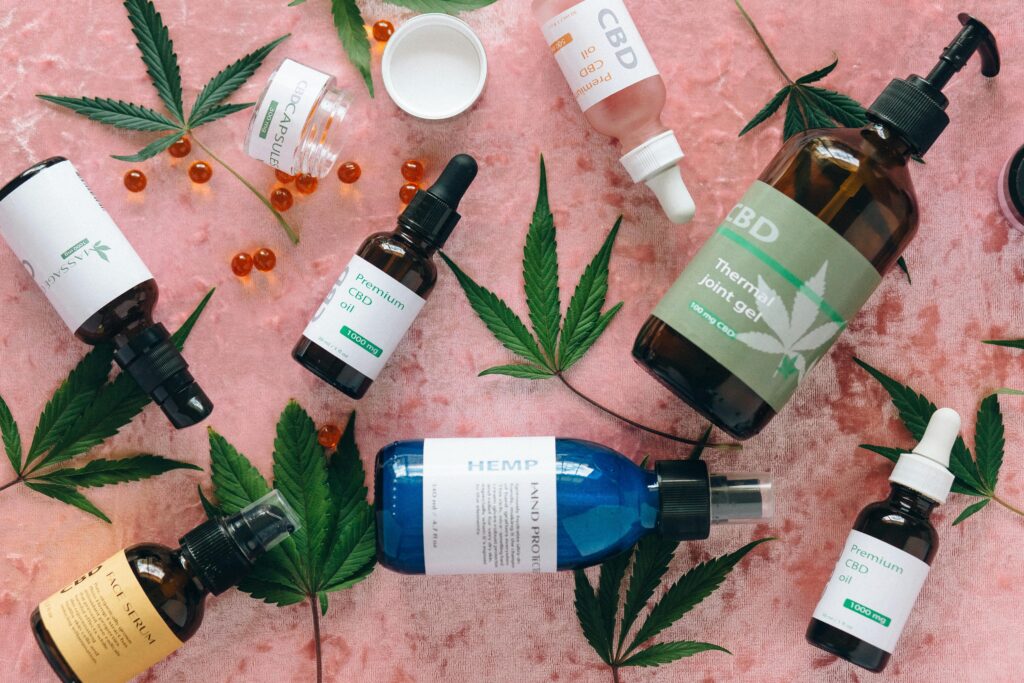Flat lay of CBD products with cannabis leaves on pink fabric, perfect for wellness theme.